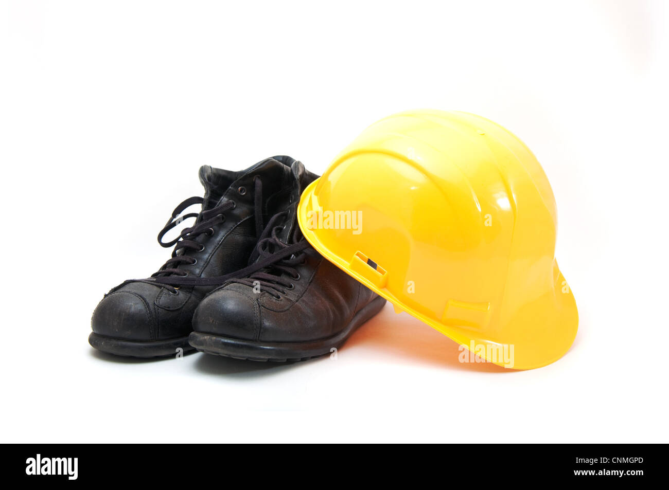 Casque jaune et des bottes en cuir ancien, de l'équipement de protection dans l'industrie de la construction. Banque D'Images