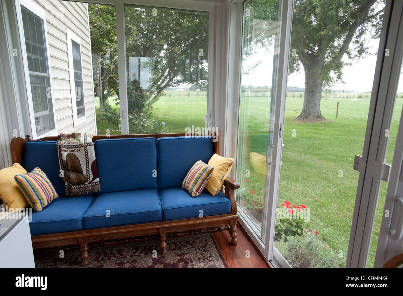 Un ancien canapé banc placé contre une fenêtre dans la véranda d'une maison Banque D'Images
