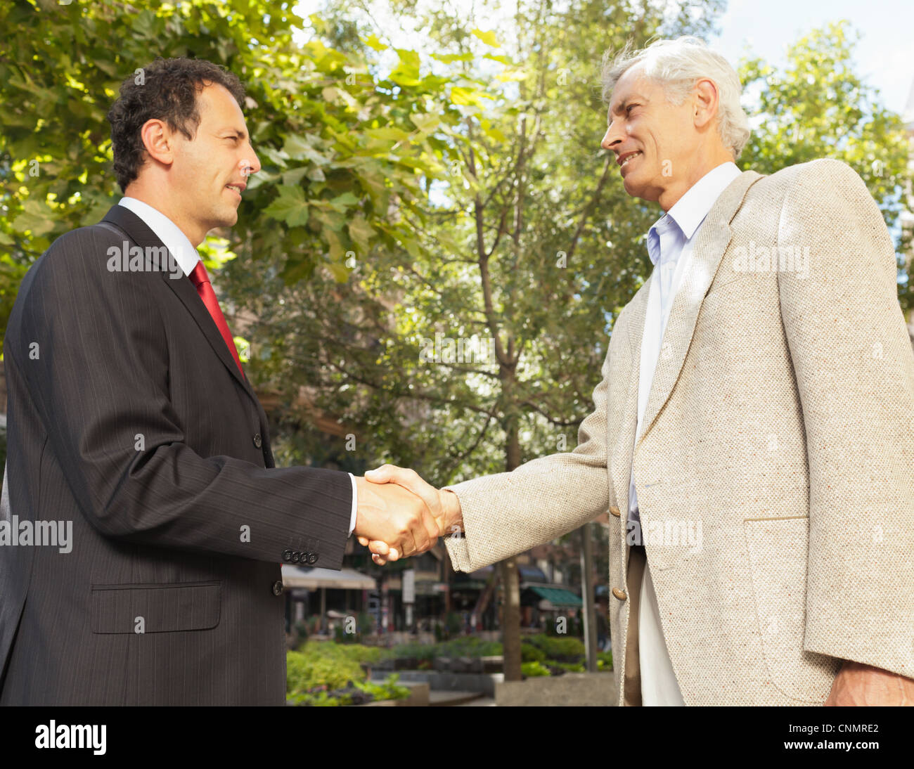Businessmen shaking hands outdoors Banque D'Images