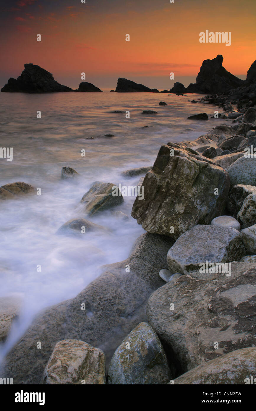 Voir des vagues sur les rochers au coucher du soleil, la baie Mupe Lulworth, Estate, Dorset, Angleterre, avril Banque D'Images