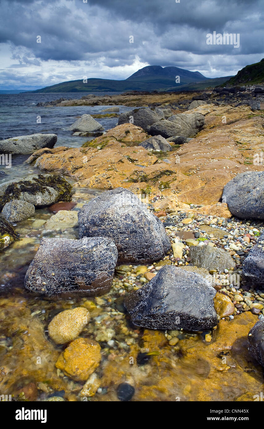 Vue sur la côte rocheuse, avec la montagne Beinn Bharrain en distance, Machrie Bay, île d'Arran, Firth of Clyde, en Écosse, juin Banque D'Images