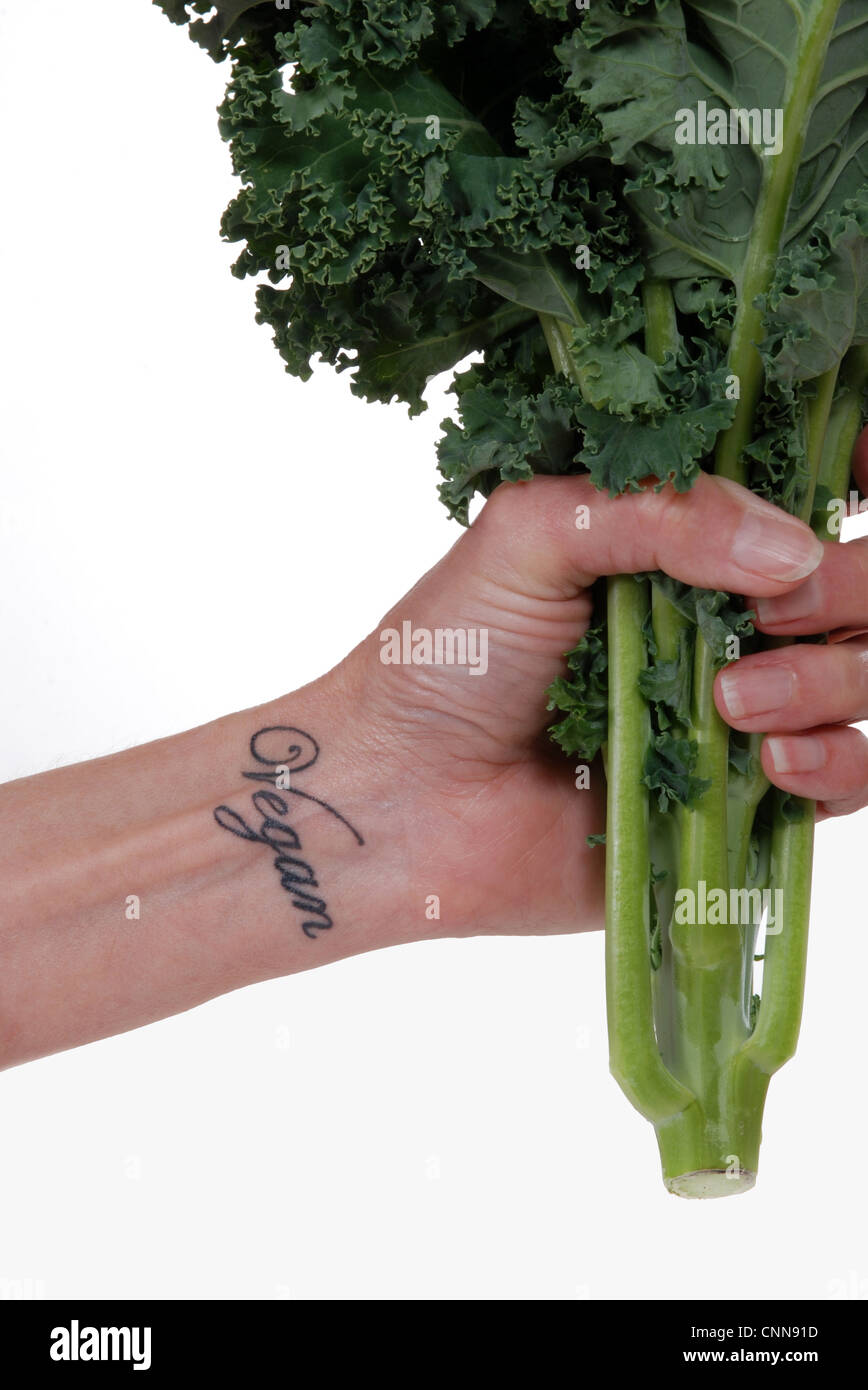 Gros plan du hand holding fresh kale, 'vegan' tatouage au poignet Banque D'Images