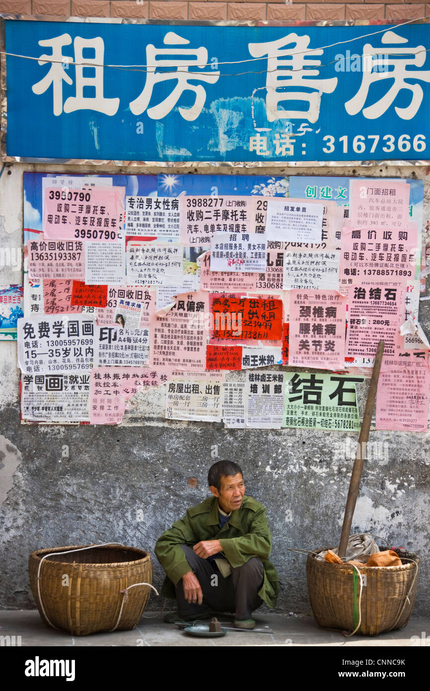 L'homme par mur avec affiches, Guilin, Guangxi, Chine Banque D'Images