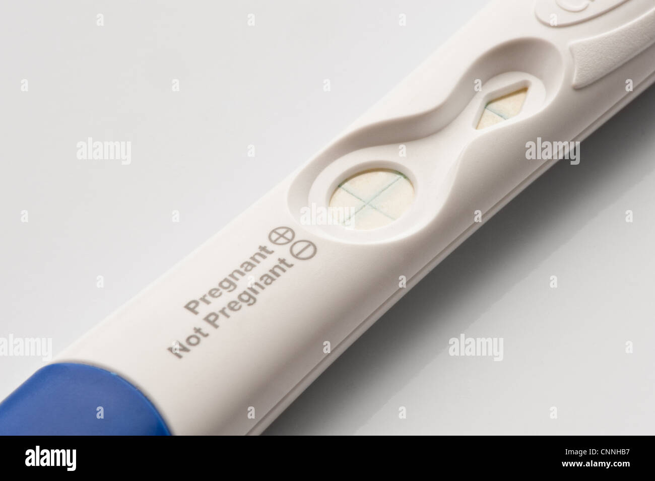 Un test de grossesse blanc bâton avec un bouchon bleu présentant un résultat positif. Banque D'Images