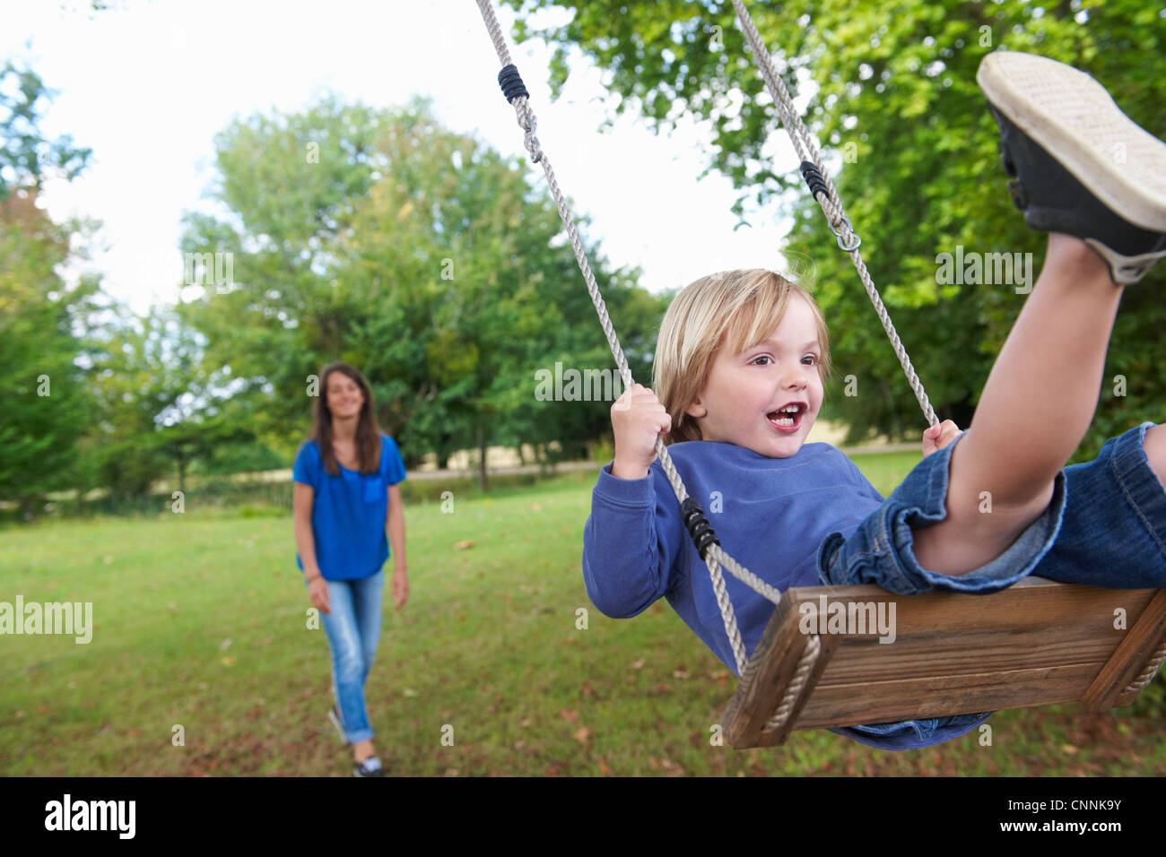 Garçon jouant sur swing in backyard Banque D'Images
