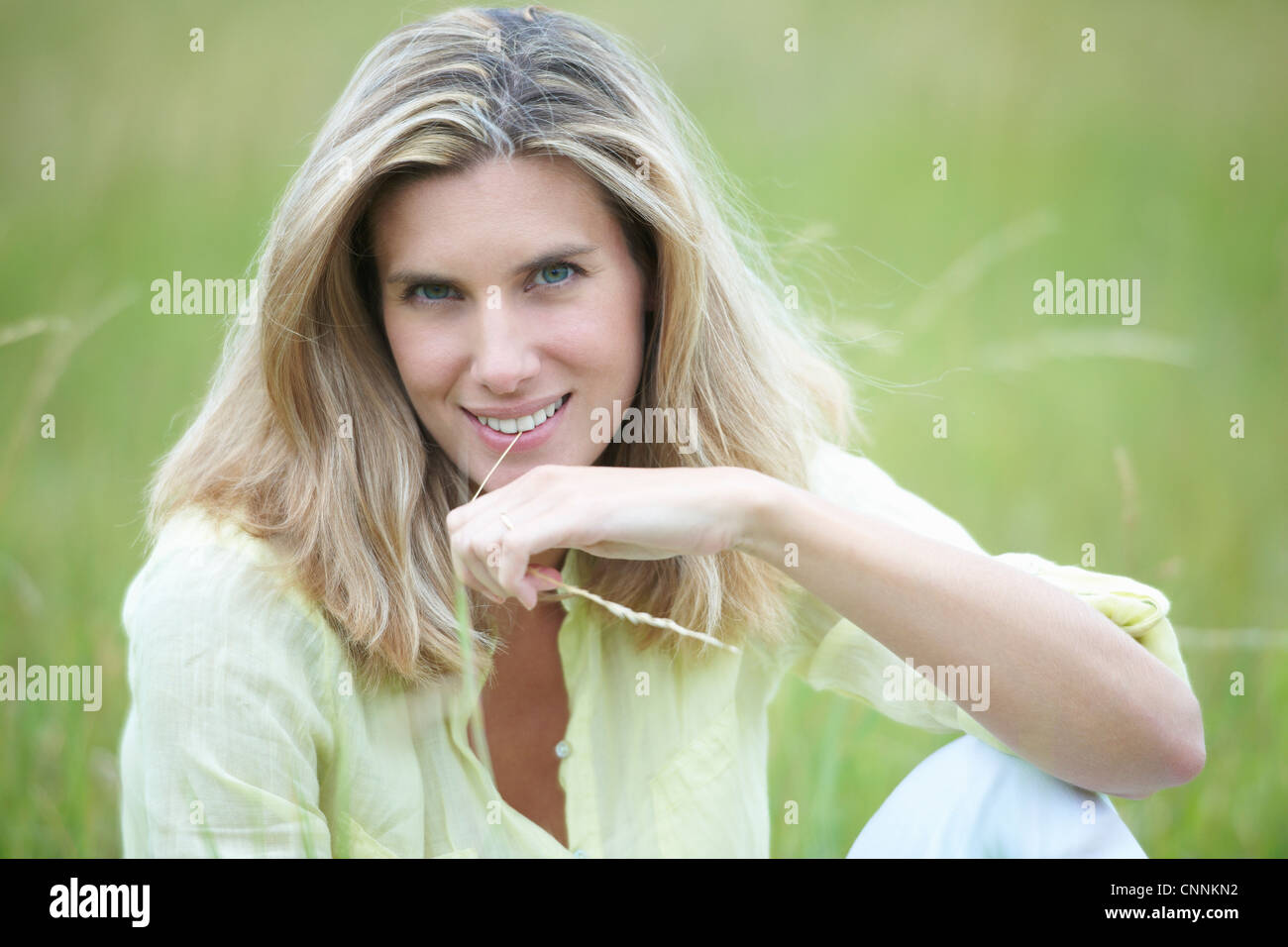Smiling woman sitting in wheat field Banque D'Images