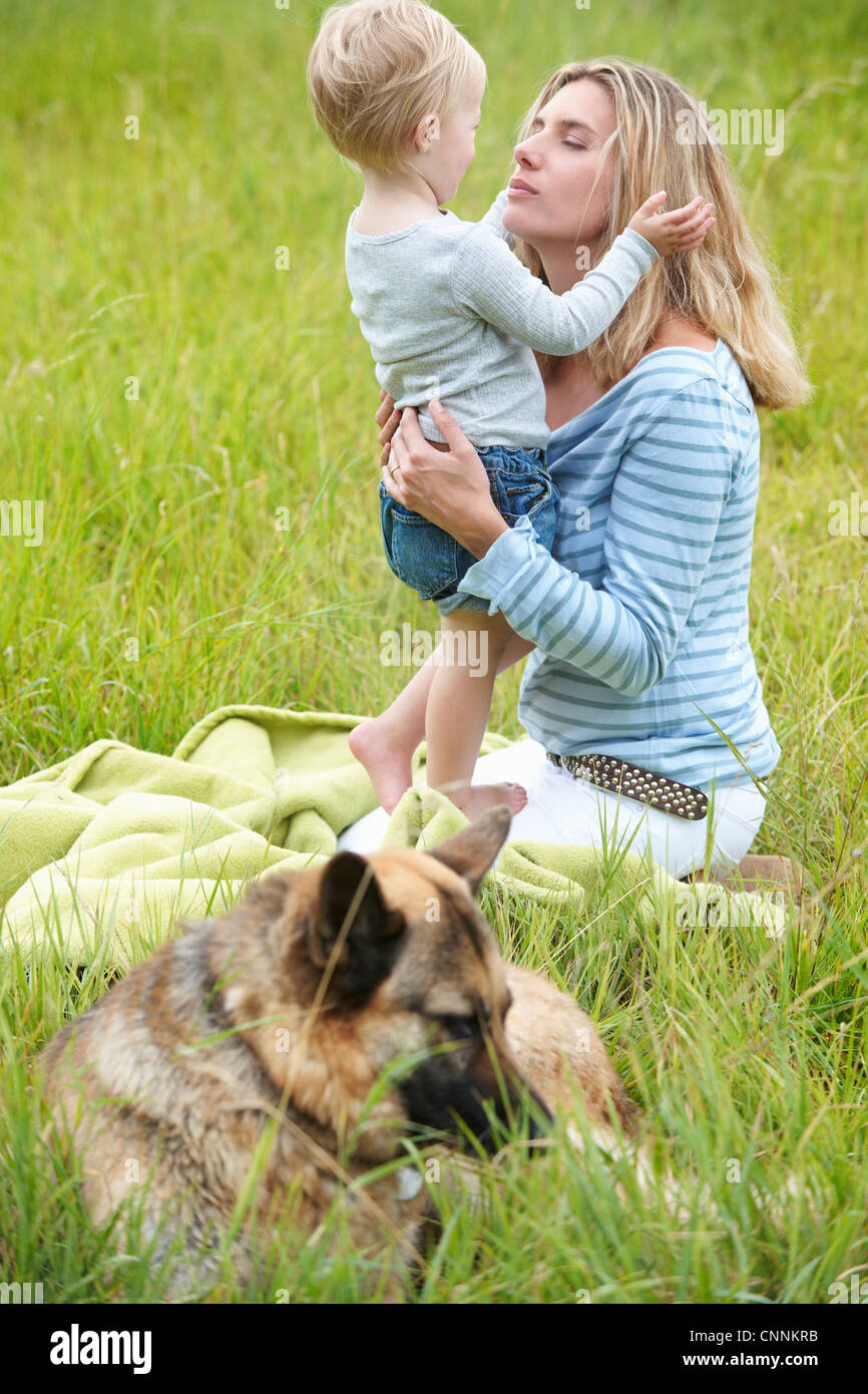 La mère et le fils assis dans l'herbe avec chien Banque D'Images