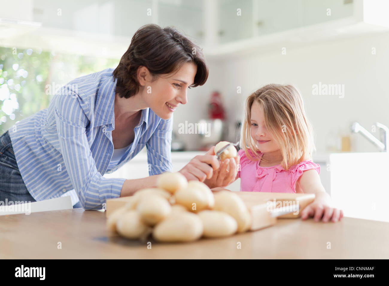Mother helping daughter peler les pommes de terre Banque D'Images