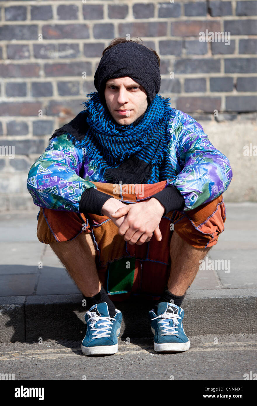 Portrait d'un jeune homme branché assis sur un trottoir, Brick Lane, Londres, Angleterre, Royaume-Uni. Banque D'Images