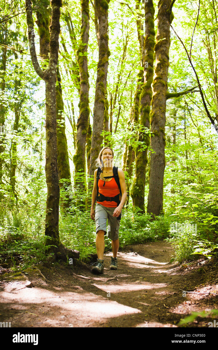 Une femme marche d'un sentier dans la forêt, si peu de trail, Washington, USA. Banque D'Images