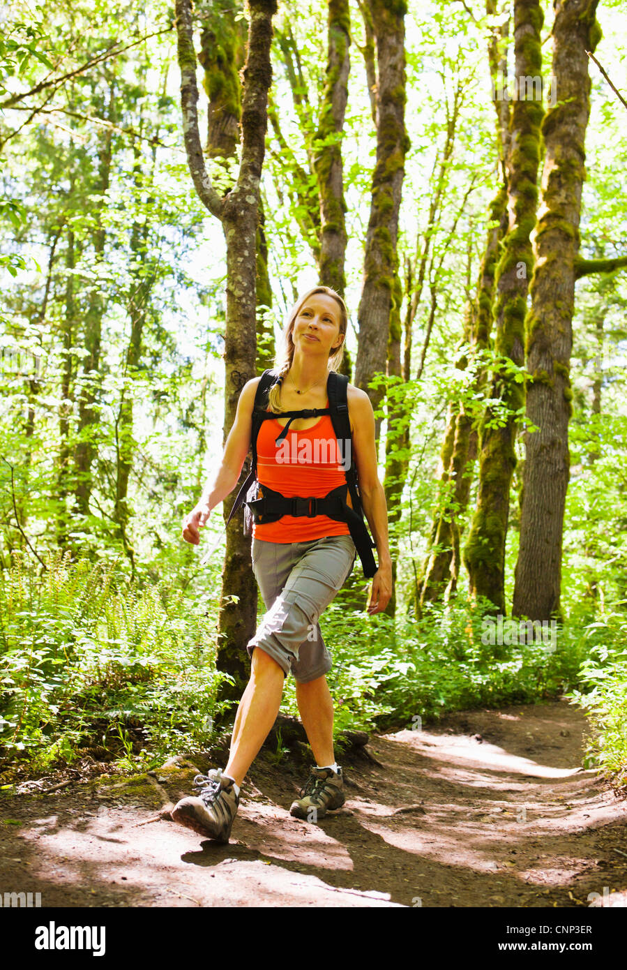Une femme marche d'un sentier dans la forêt, si peu de trail, Washington, USA. Banque D'Images