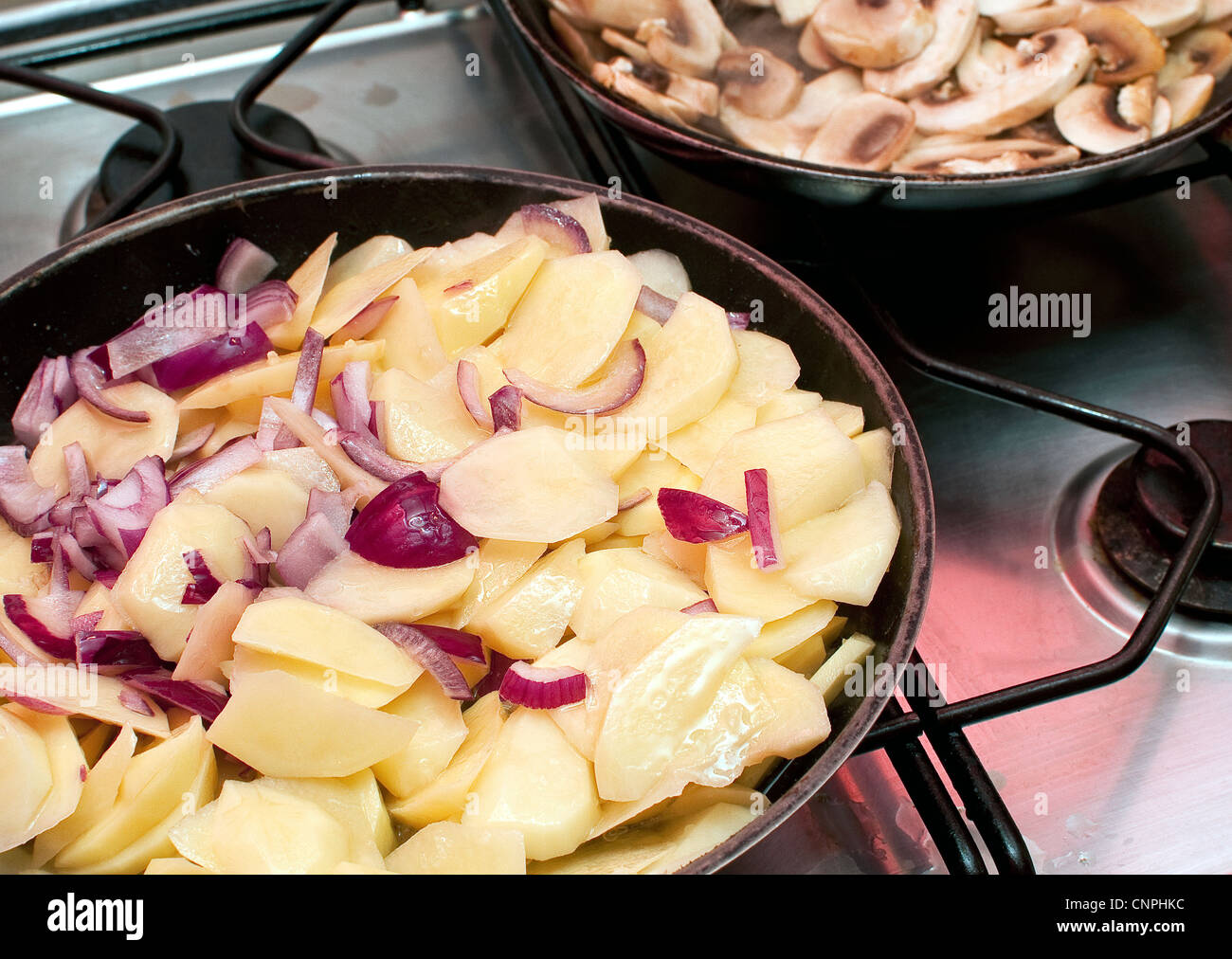 Pommes de terre à frire l'oignon et les champignons sur une cuisinière vitrocéramique pour faire une omelette espagnole tortilla Banque D'Images