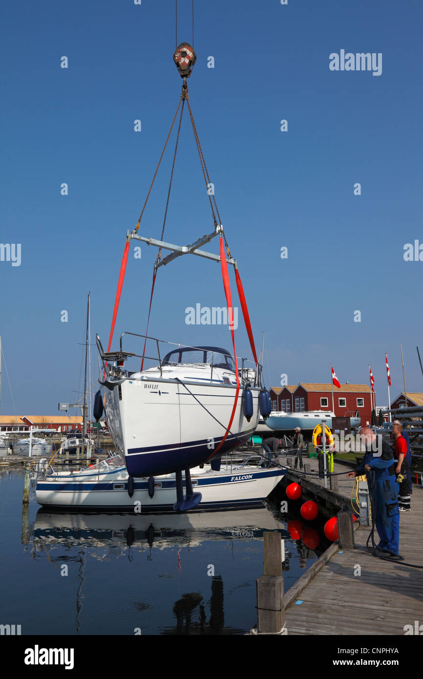 Bateau à voile d'être hissé dans le port par une grue pour la saison estivale à partir de l'entreposage hivernal Banque D'Images