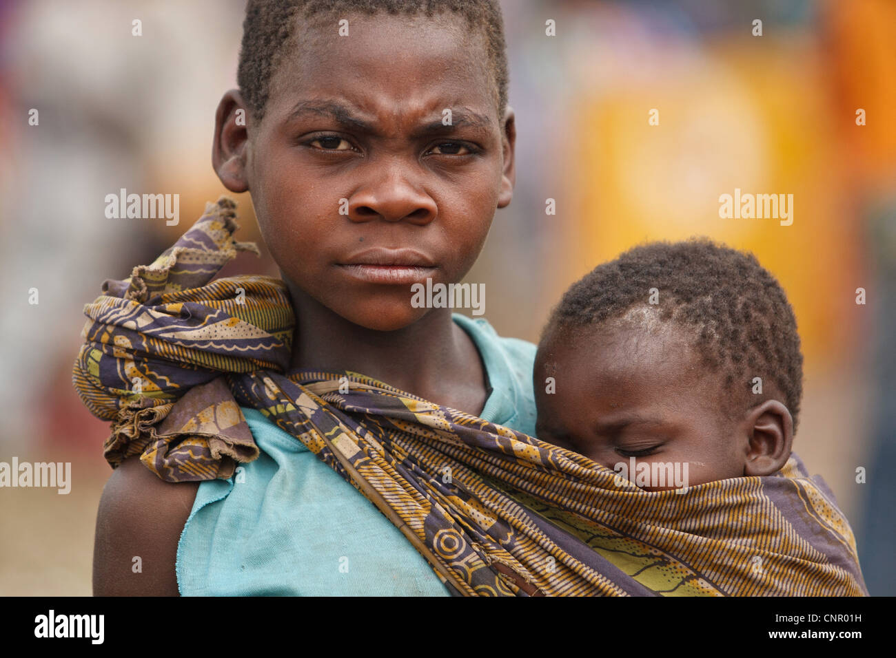 Une jeune fille porte un enfant plus jeune à l'IDP Miketo, règlement de la province du Katanga, République démocratique du Congo Banque D'Images