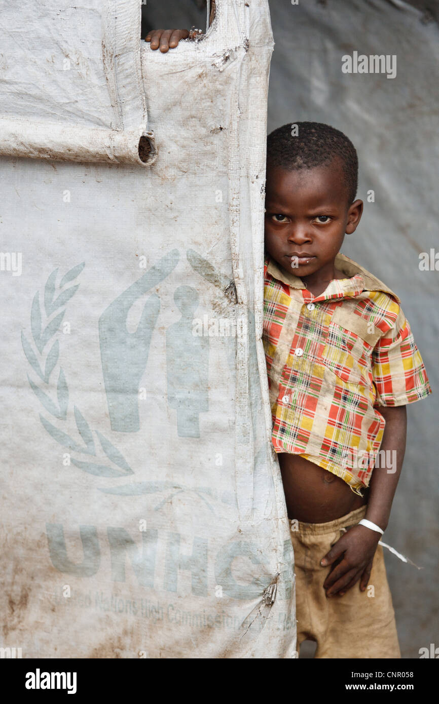 Un garçon se tient dans l'embrasure d'un abri temporaire faite par le HCR a fourni à la bâche à Miketo règlement IDP, Katanga, RDC Banque D'Images