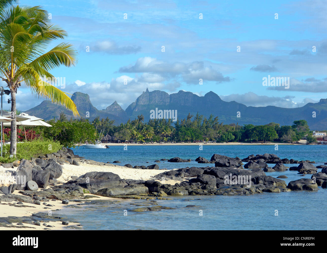 Plage et les rochers en face de l'hôtel Oberoi, sur l'île Maurice avec des montagnes au loin. Banque D'Images