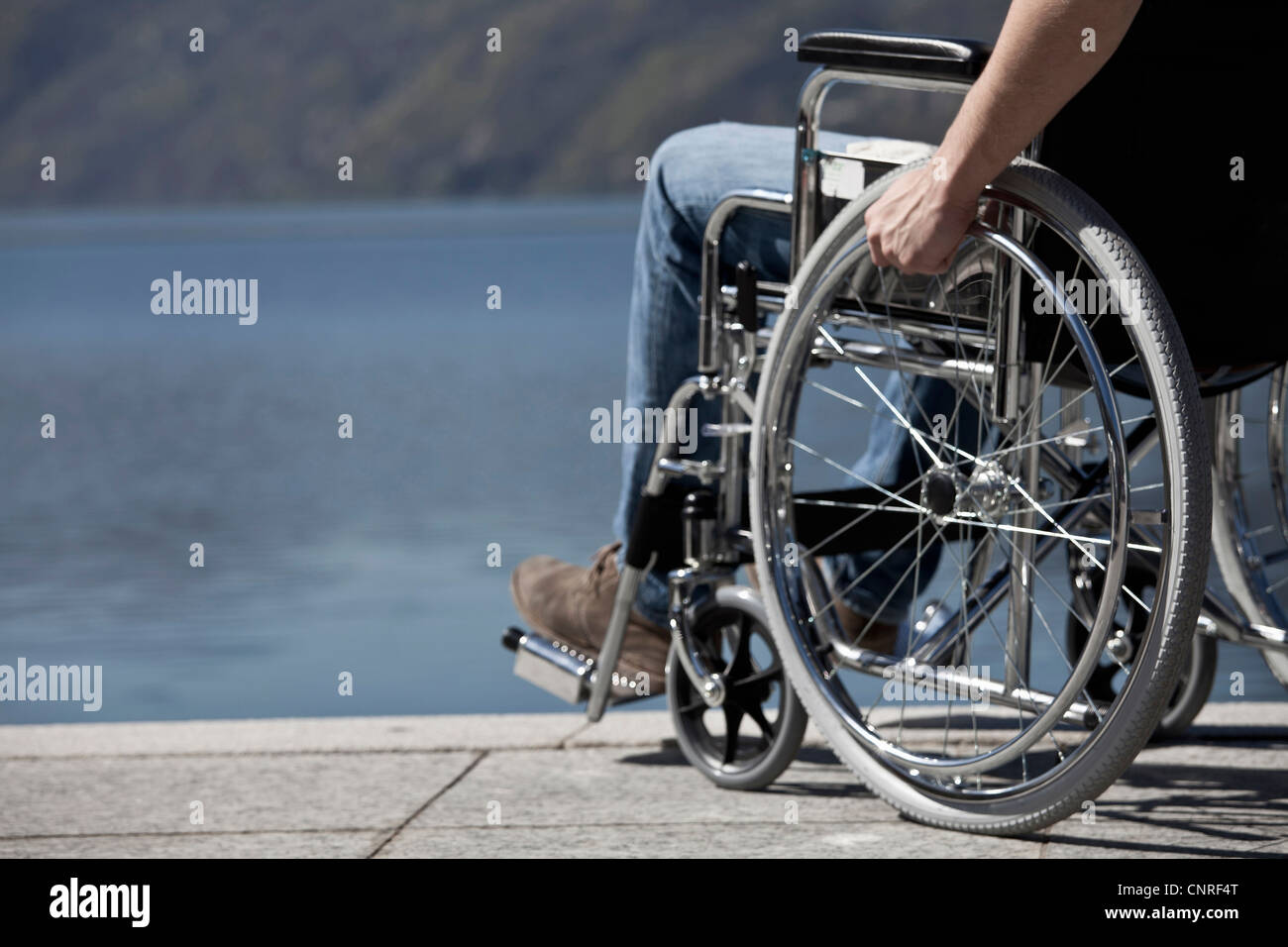 L'homme assis en fauteuil roulant par l'eau Banque D'Images