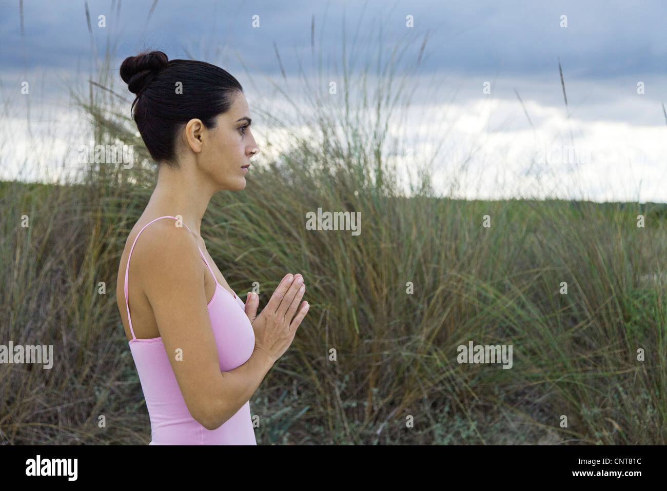 Femme mature en position de prière en plein air, side view Banque D'Images