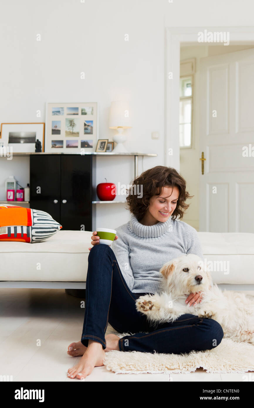 Woman petting dog in living room Banque D'Images