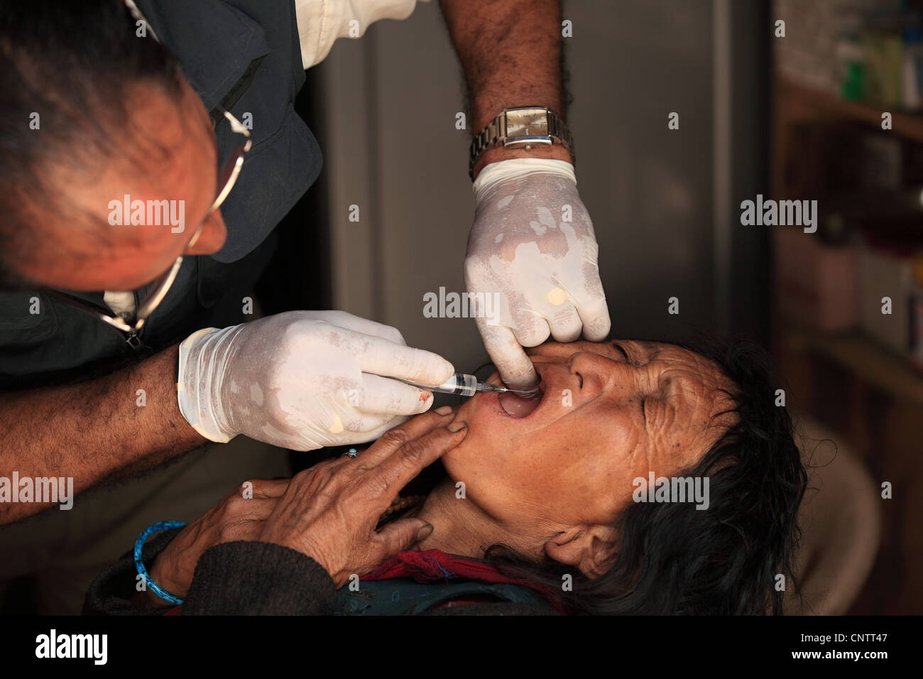 Dentiste rural népalais avec vieille femme malade au Népal Banque D'Images