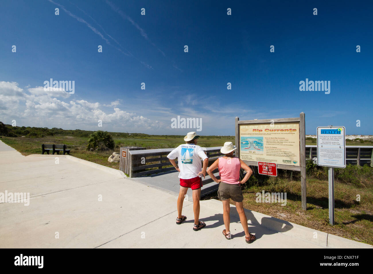 Vieux couple lisant un panneau d'information, d'avertissement à propos de courants de retour. Anastasia State Park - Saint Augustin - Floride Banque D'Images