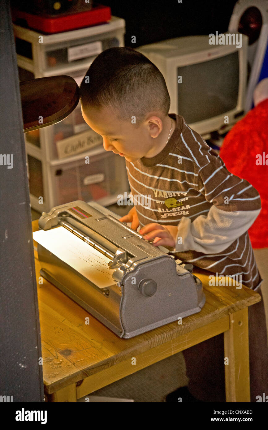 Un garçon aveugle sur une machine à écrire braille types au Blind Children's Learning Centre à Santa Ana, CA. Banque D'Images