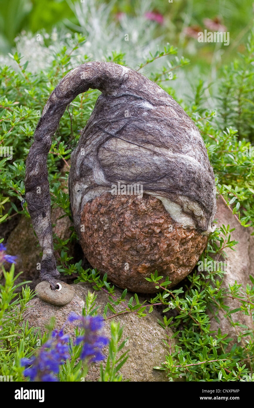 Pierre se sentait 'troll' servant de décoration de jardin : une pierre naturelle équipée de bouchons de laine feutrée est debout dans un lit de fleur, Allemagne Banque D'Images