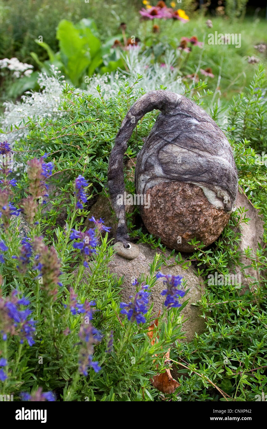 Pierre se sentait 'troll' servant de décoration de jardin : une pierre naturelle équipée de bouchons de laine feutrée est debout dans un lit de fleur, Allemagne Banque D'Images