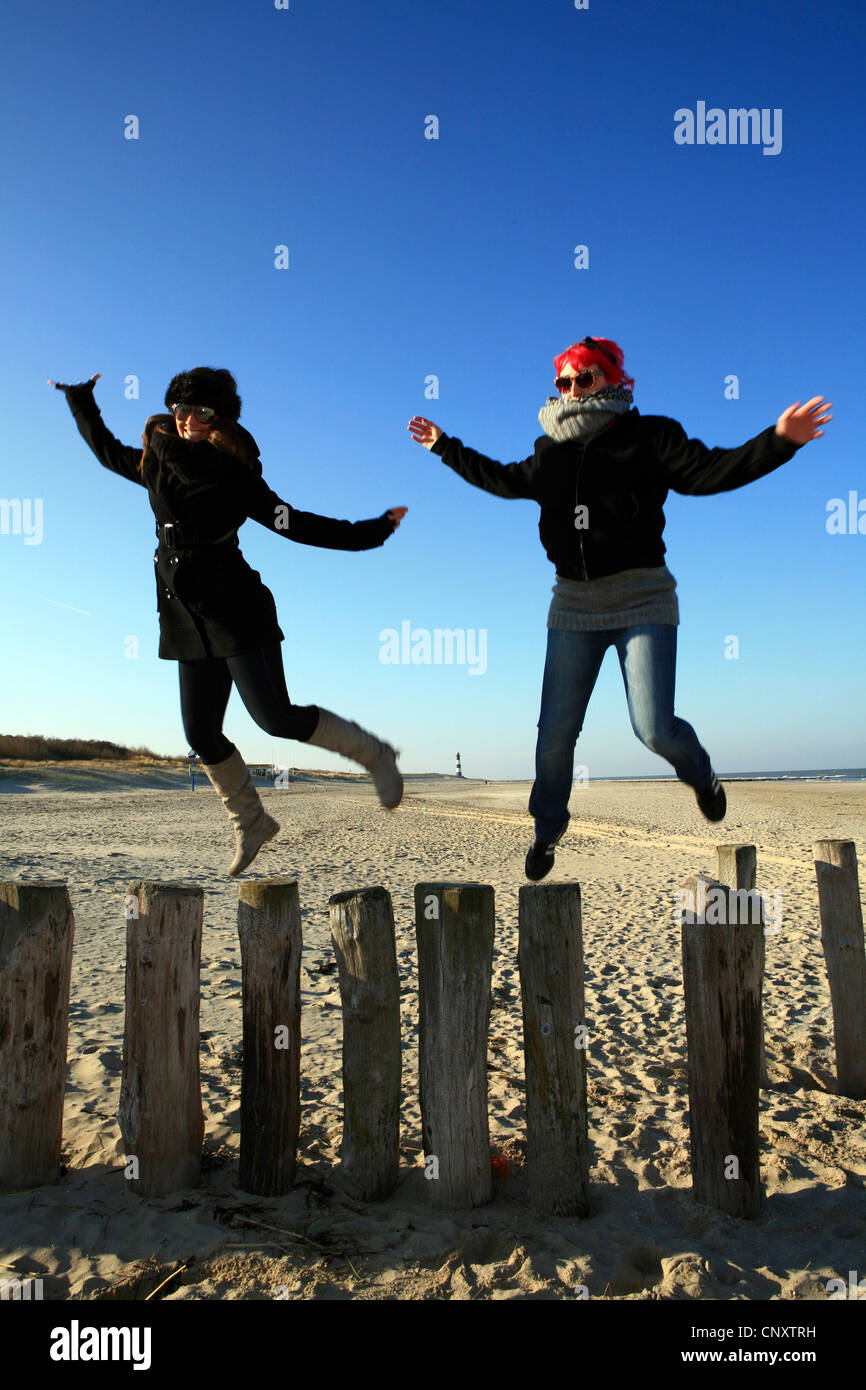 Deux jeunes femmes s'frolicly sautant d'épis à la plage, Pays-Bas, Zeeland, Breskens, Sluis Banque D'Images