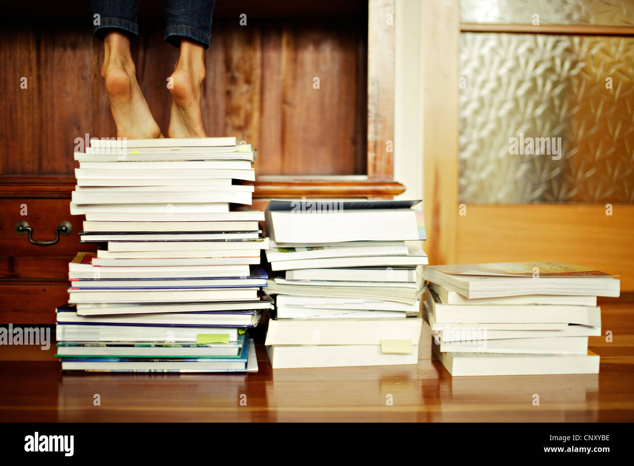 Jeune fille se tient sur la pointe des pieds pile of books Banque D'Images