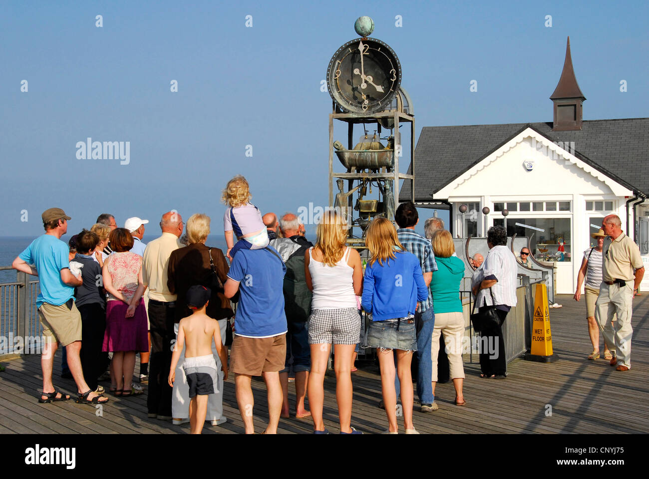 - Suffolk Southwold pier - été foule attendant de voir le comique horloge à eau effectuer sur l'heure - du soleil Ciel bleu Banque D'Images