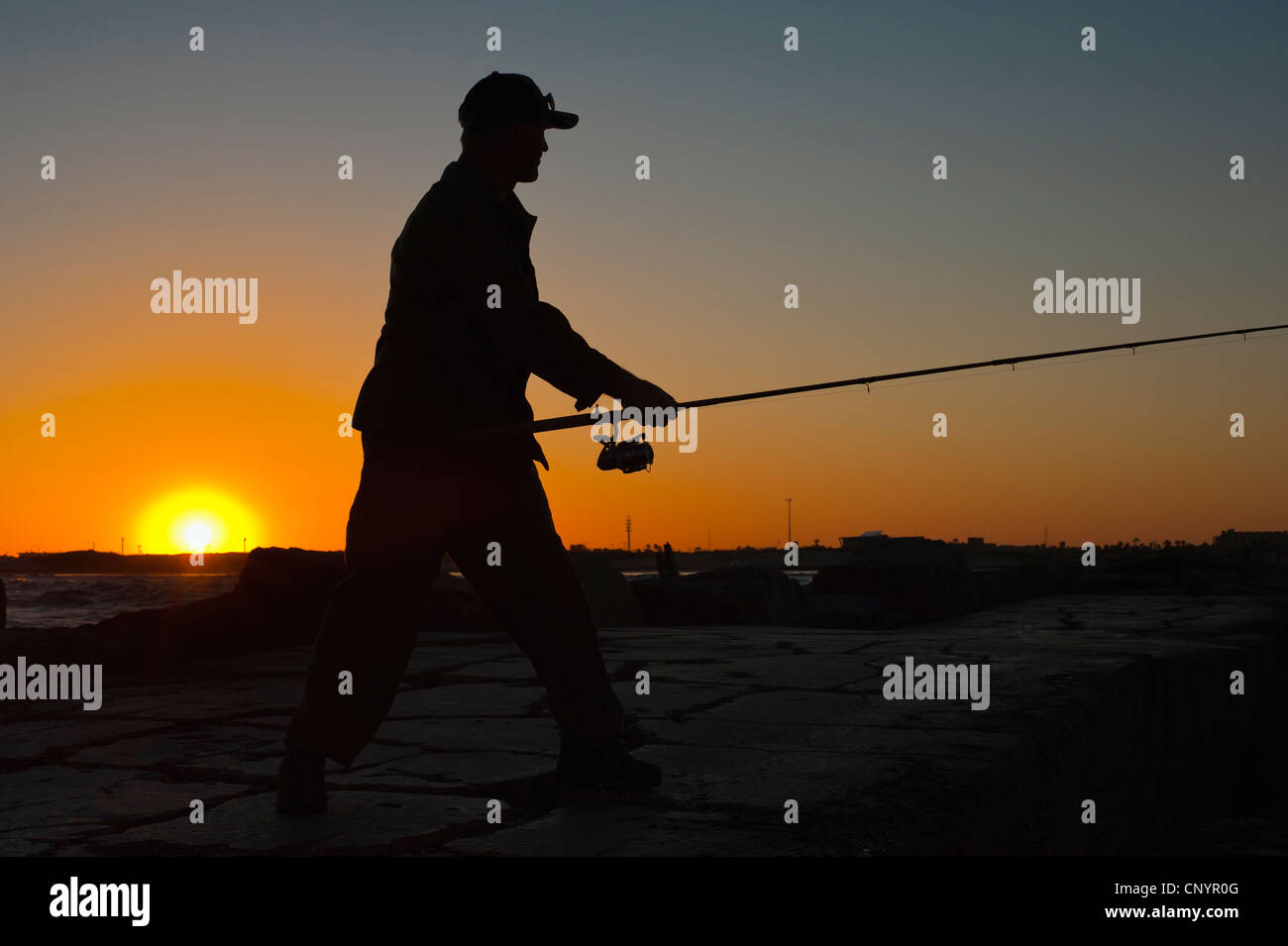 Sunset silhouette de Fisherman casting la canne à pêche Banque D'Images