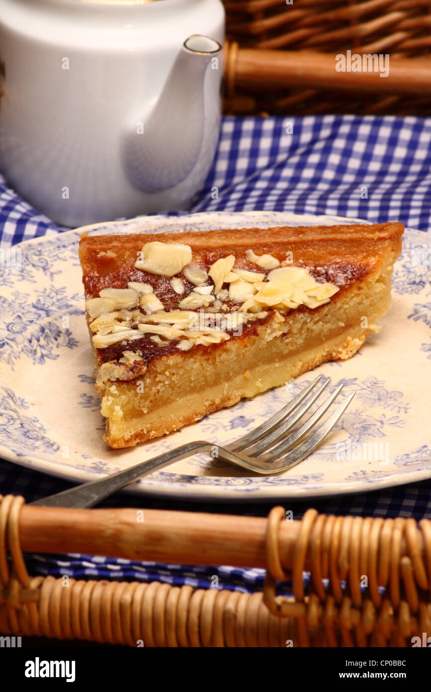 Une tranche de pudding Bakewell tart servi avec une tasse de thé sur un plateau à thé vintage, Derbyshire, Royaume-Uni Banque D'Images