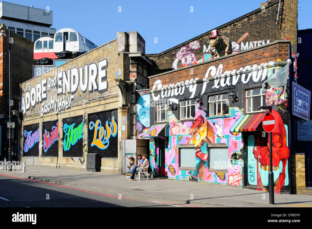 Voitures de train à tube recyclées utilisées comme studios d'artistes perchés au-dessus de vieux murs de viaduc de chemin de fer en dessous des graffitis arty dans Shoreditch East London Angleterre Royaume-Uni Banque D'Images