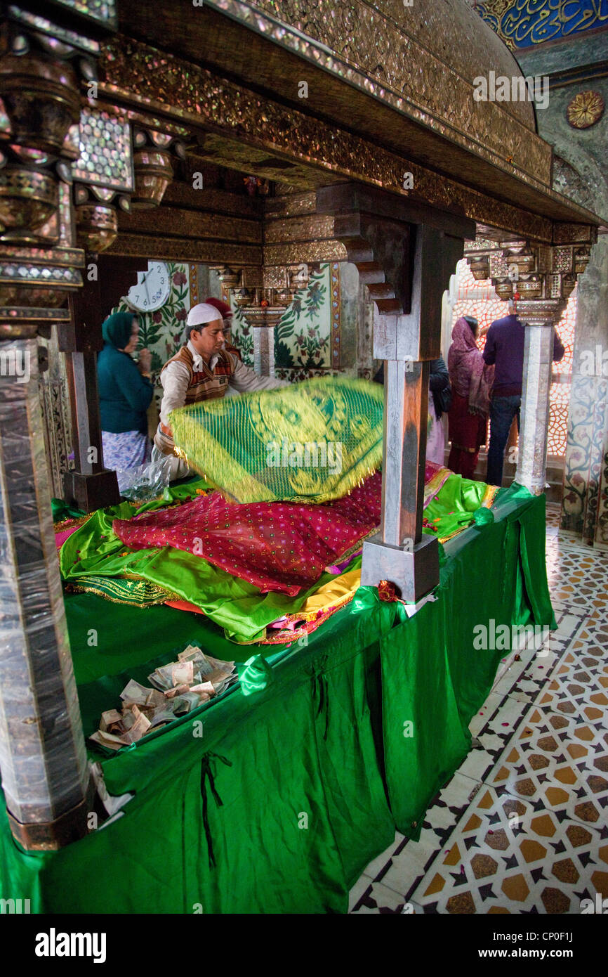 Fatehpur Sikri, l'Inde. À l'intérieur de mausolée de Cheikh Salim Chishti un gardien met un tissu offrant sur la tombe. Banque D'Images