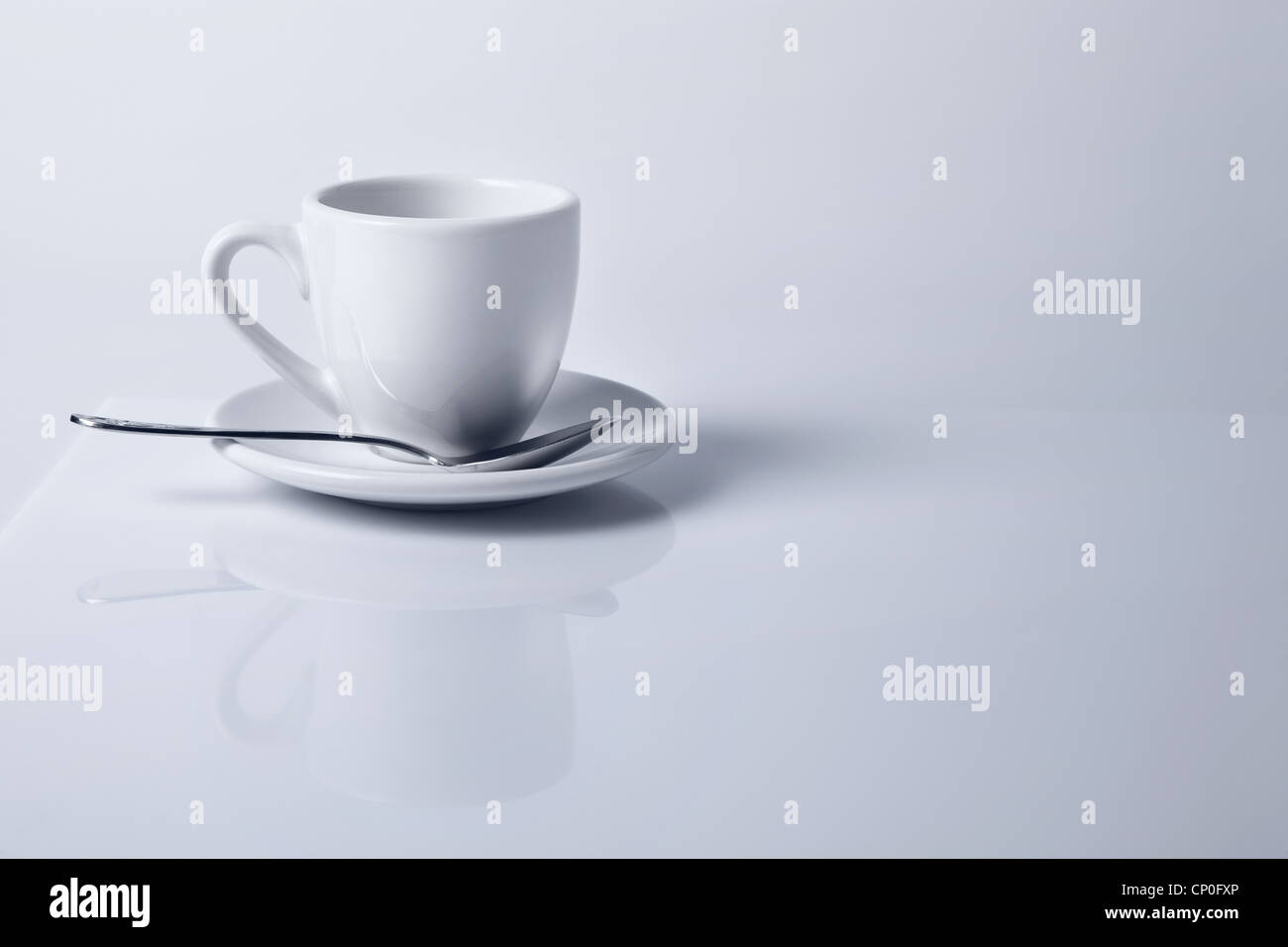 La tasse de café vide blanc se reflétant dans la surface de table blanc Banque D'Images
