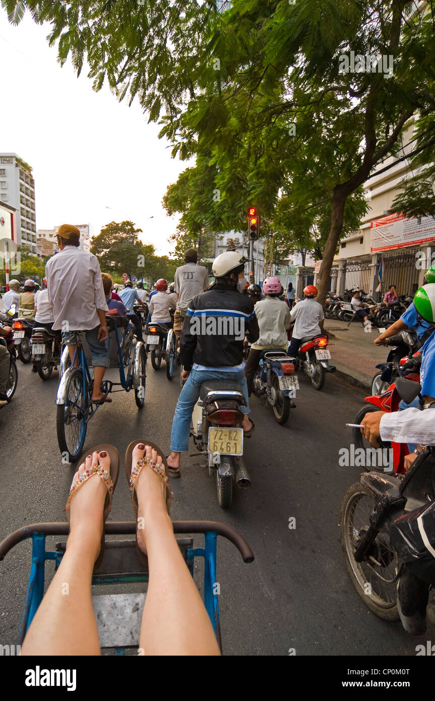 Vue verticale d'un tourisme de l'Ouest sur un cycle rickshaw voyageant à travers le trafic sur les rues folles de Ho Chi Minh Ville. Banque D'Images