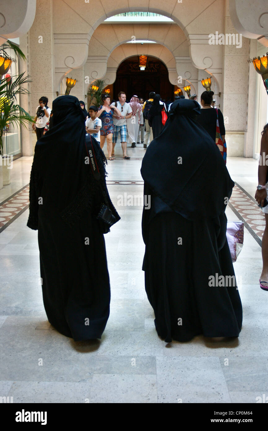 Deux femmes en costume traditionnel à l'Hôtel Atlantis The Palm, Palm Jumeirah, Dubai, Émirats arabes unis. L'un a un appareil photo Canon. Vue arrière. Banque D'Images