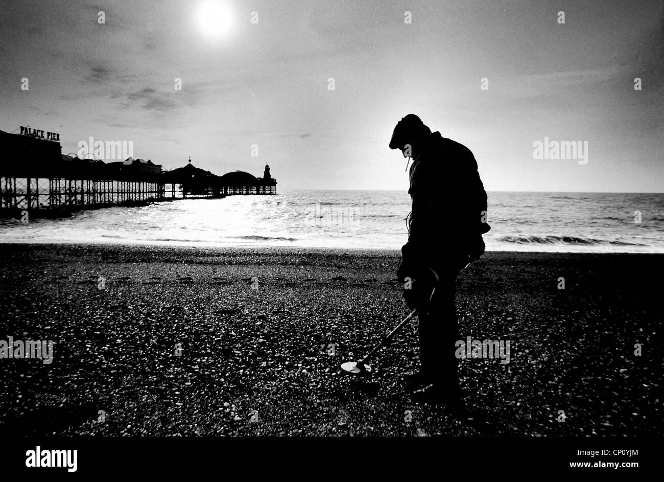 L'homme se découpant sur la plage de Brighton en utilisant un détecteur de métal par l'ancien Palace Pier UK circa 1984 Banque D'Images