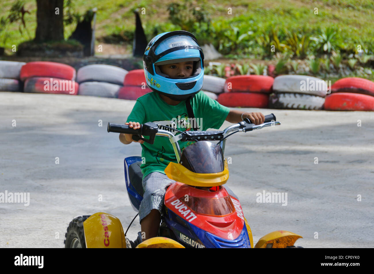 Les jeunes 4-5 ans garçon casque bleu équitation enfants Quad ATV racing sur la race track - Puerto Galera, Philippines, Asie Banque D'Images