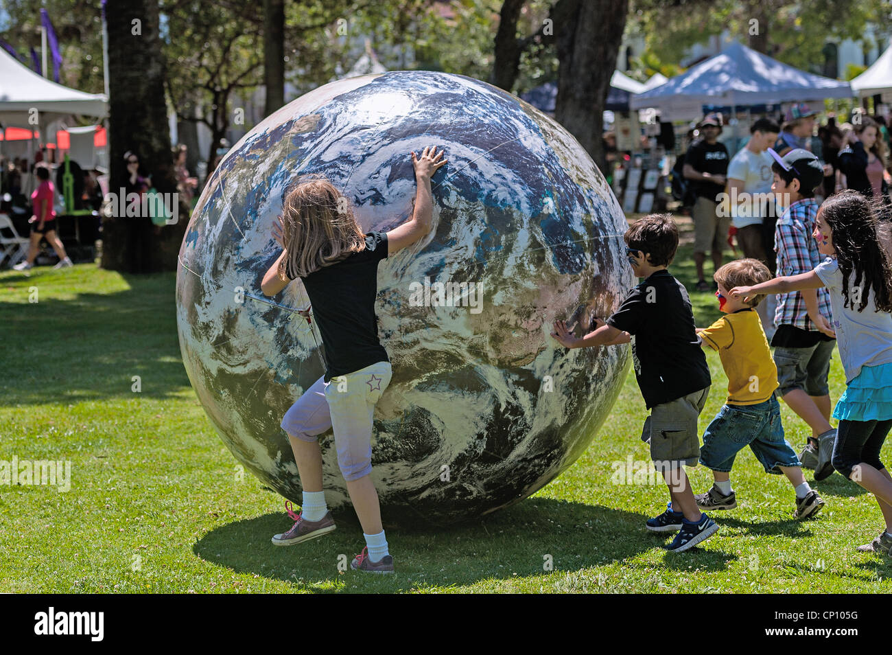 L'enfant doit lancer un géant 'planète Terre' ball gonflable lors de l'assemblée 'le jour de la Terre' passe à Alameda Park à Santa Barbara, CA Banque D'Images