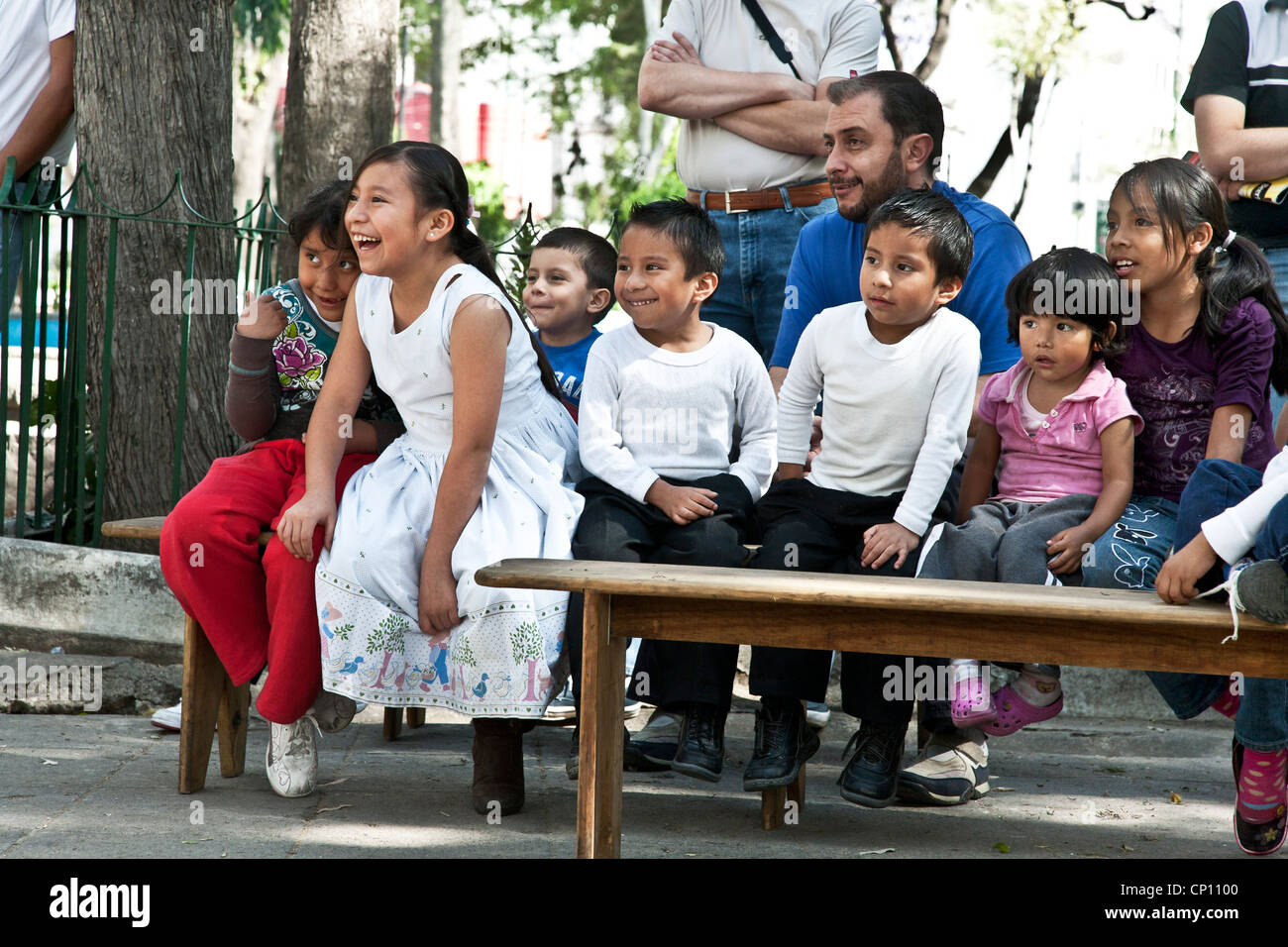 Adultes adultes & enfants mexicains répondre avec plaisir à des pitreries de clown magicien d'effectuer à l'extérieur dans Luis Cabrera park district Mexique Roms Banque D'Images