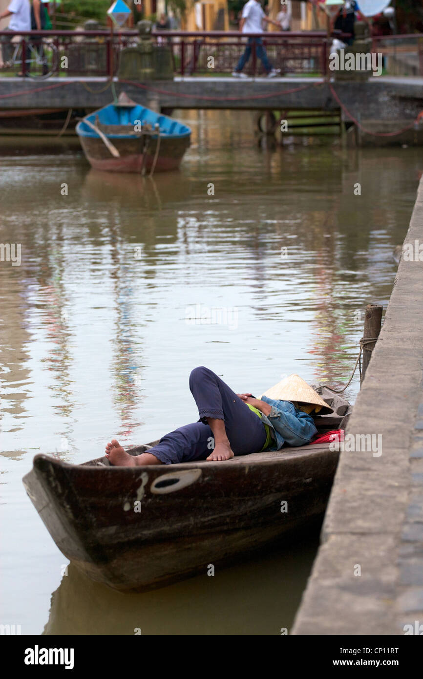 Un chauffeur de taxi rivière ayant un sommeil sur le bateau à Hoi An, au Vietnam. Banque D'Images
