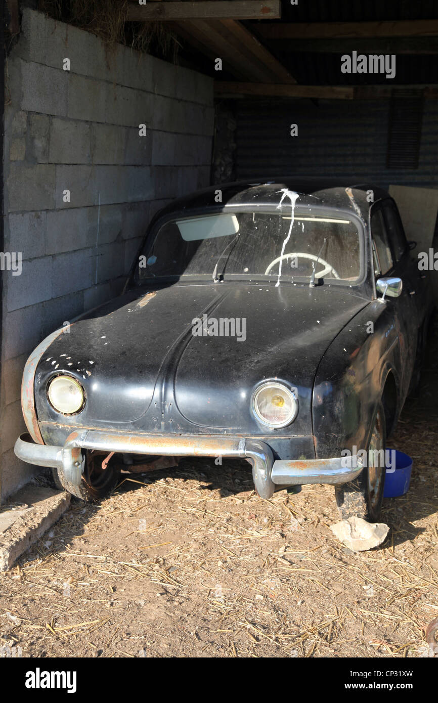 C'est une vieille voiture noire abandonnée dans un garage quelque part dans la campagne profonde dans une ferme en Normandie, France. La voiture est sale Broken Banque D'Images