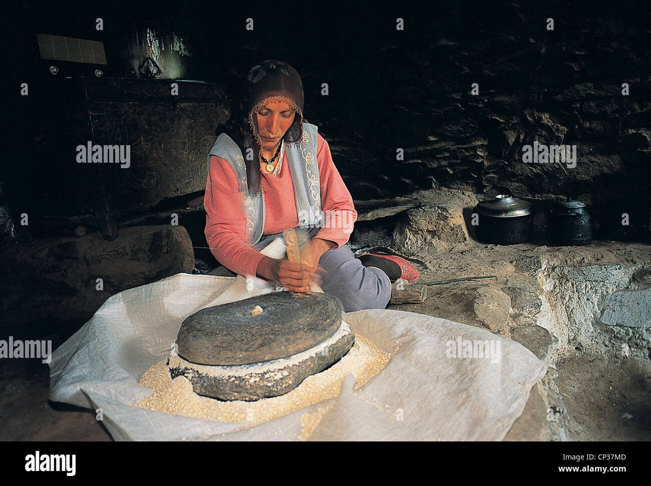 Femme de maïs broyage pour faire un pain de maïs sur un moulin manuel traditionnel en pierre Şingalik Batman Turquie Banque D'Images