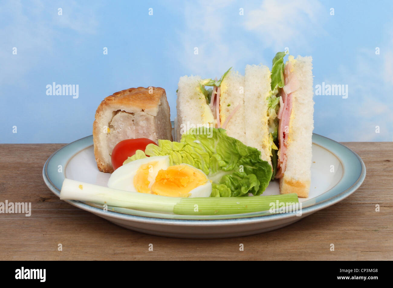 Une assiette de nourriture pique-nique sur une planche en bois contre un ciel d'été bleu Banque D'Images