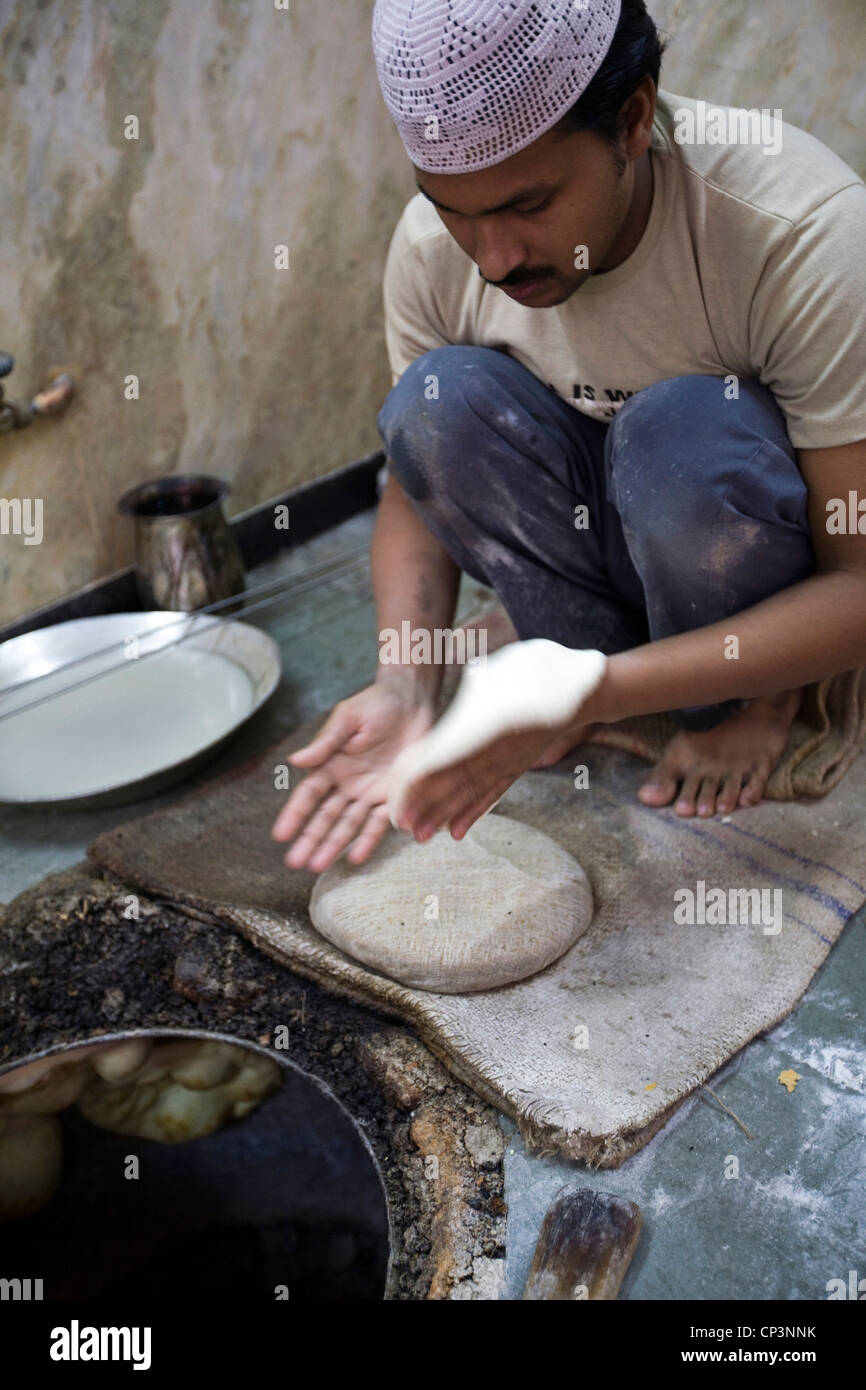 L M Rahman le pétrissage et la cuisson du pain naan frais dans le four tandoor à Karim's Restaurant, Delhi, Inde Banque D'Images