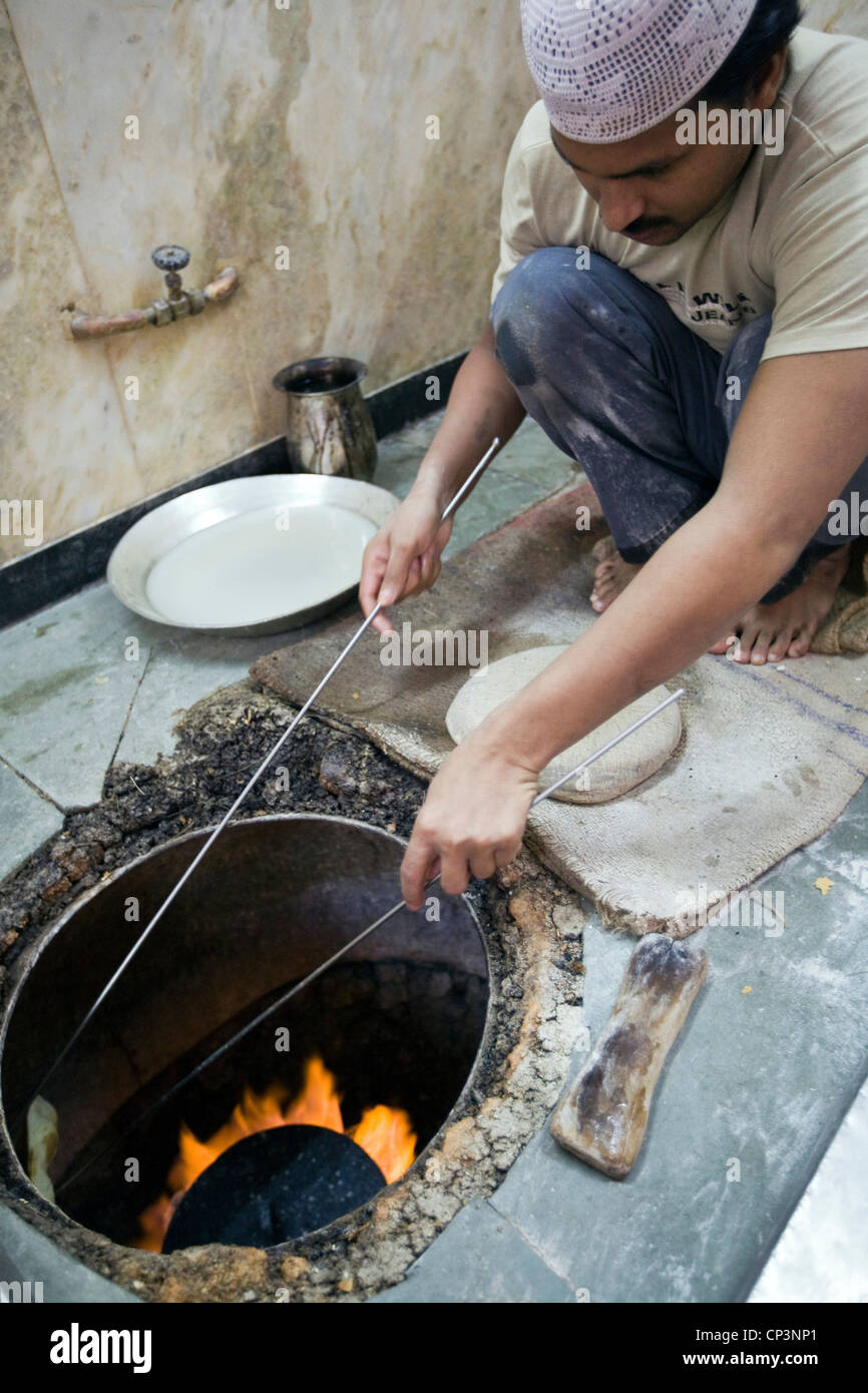 L M Rahman la préparation et la cuisson du pain naan frais dans le four tandoor à Karim's Restaurant, Delhi, Inde Banque D'Images