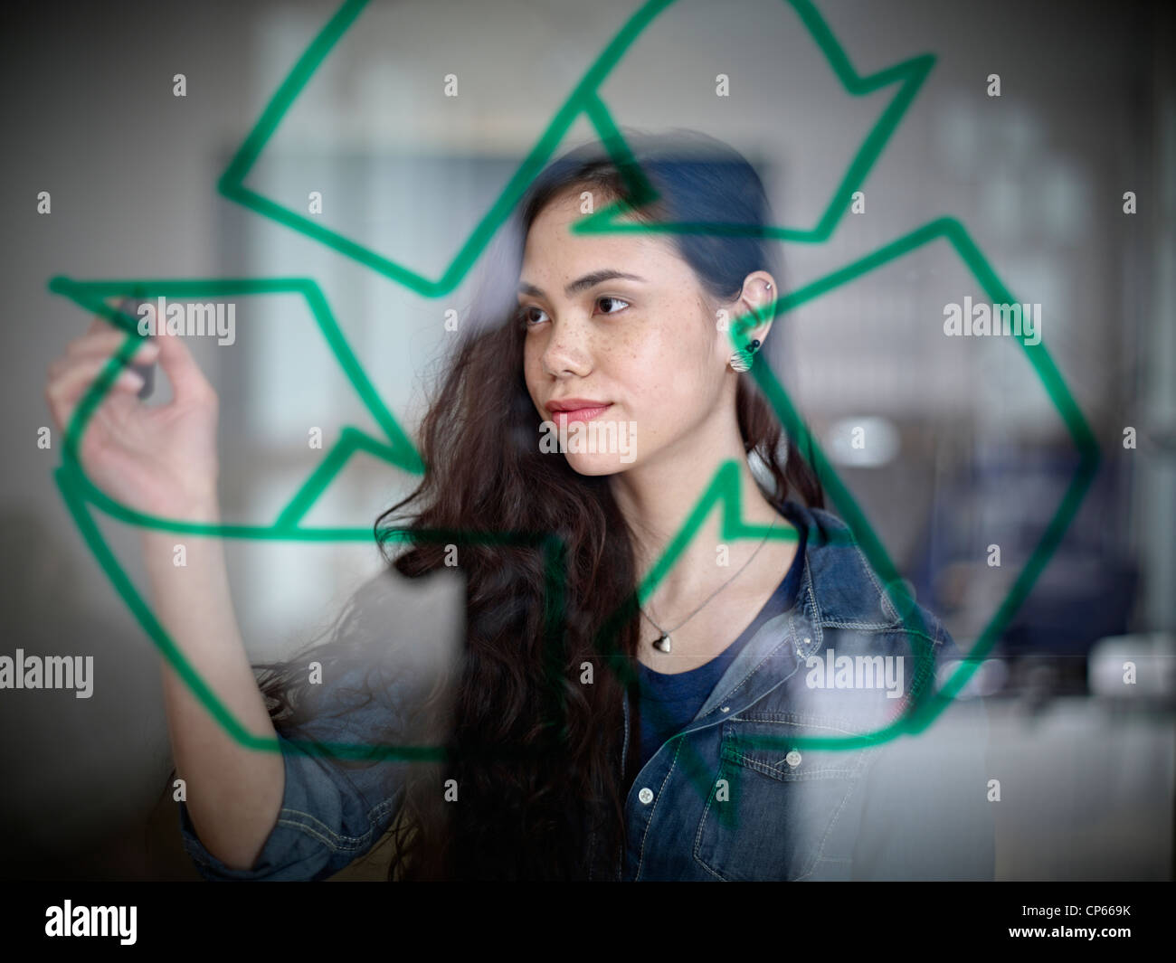 Germany, Cologne, young woman encombrement symbole de recyclage sur verre Banque D'Images