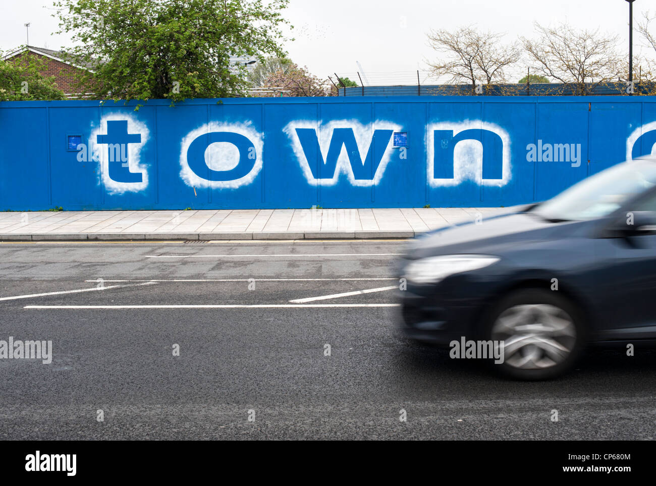Sur le panneau de la commune clôture bleue avec la voiture en premier plan (avec le flou) à Canning Town Londres Royaume-Uni. Scène urbaine dans la région de East London Banque D'Images